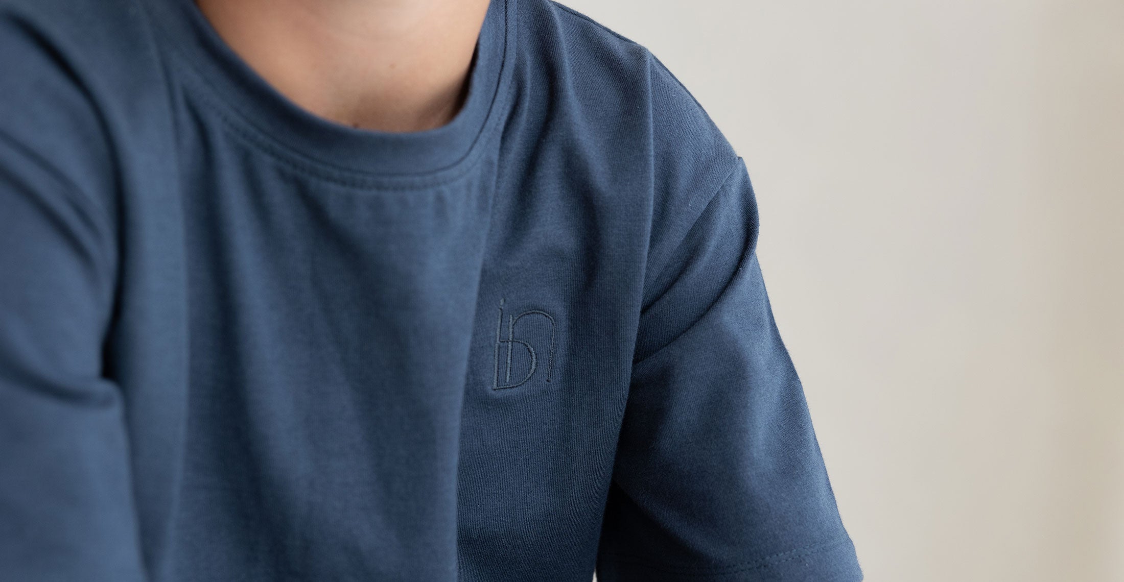 Close-up of a navy blue long-sleeve crewneck shirt featuring a subtle embroidered “ibn” logo on the chest. The fabric has a soft, cozy texture, emphasizing comfort and minimalist design.