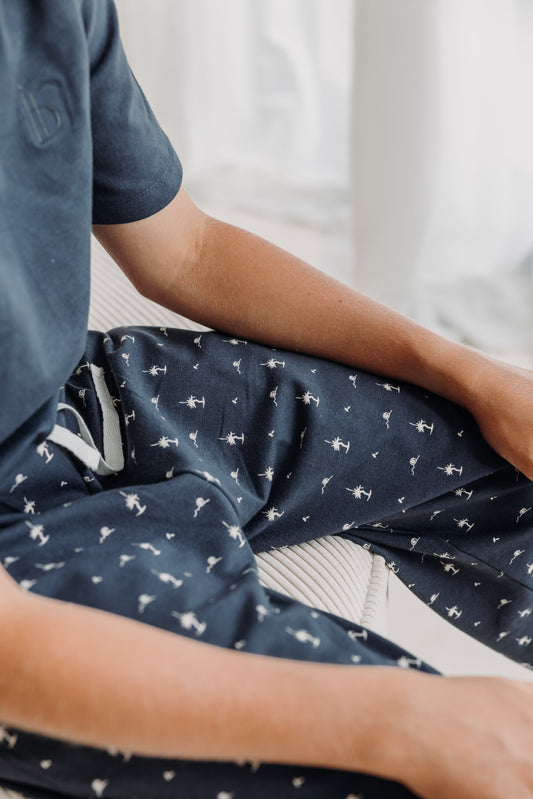 Close-up of Inspired by Nature SA kids' pajama pants in navy blue with white deer print and cream drawstring. Made from organic cotton for cozy, breathable sleepwear that blends nature-inspired design with sustainable comfort.